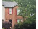 This brick townhouse boasts red shutters, green bushes, and a tree in front at 338 Saratoga Pl, Riverdale, GA 30296