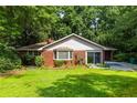 Charming brick home featuring a well-manicured lawn, mature trees, and a concrete driveway at 1102 Rogeretta Ne Dr, Atlanta, GA 30329
