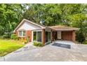 Charming brick home featuring a well-manicured lawn, mature trees, and a concrete driveway at 1102 Rogeretta Ne Dr, Atlanta, GA 30329