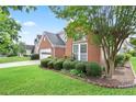 Beautiful landscaping frames the front of this classic brick home and driveway on a sunny day at 1460 Chamirey Sw Dr, Marietta, GA 30008