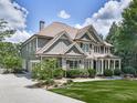 Side view of a house boasting manicured lawn, stone details, professional landscaping, and a spacious driveway at 310 River Birch Ct, Canton, GA 30114