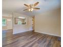 Open living room with wood-look flooring, ceiling fan, and view into the kitchen through a pass-through window at 170 Hidden Pines Dr, Covington, GA 30016