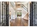 Grand foyer with hardwood floors, staircase, and ornate iron door and hardware at 6185 Masters Club Dr, Suwanee, GA 30024