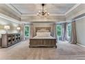 Spacious main bedroom featuring trey ceilings, neutral tones, large windows, and a rustic-style bedroom set at 6185 Masters Club Dr, Suwanee, GA 30024