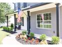 Inviting covered front porch with black columns, enhanced landscaping, and an American flag at 2720 Meridian Ct, Dacula, GA 30019