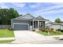 Inviting home exterior with a cozy front porch, landscaped lawn, and a gray garage door at 3026 Towne Mill Ave, Canton, GA 30114