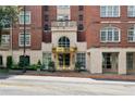 Close up of building entrance with golden doors and trim, featuring stone accents and manicured landscaping at 77 Peachtree Ne Pl # 101, Atlanta, GA 30309