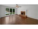 Bright living room with a brick fireplace, ceiling fan, and large windows overlooking the backyard pool at 110 Wyngate Way, Fayetteville, GA 30215