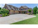 Elegant brick home featuring a three-car garage and pristine landscaping, creating a striking curb appeal at 120 Slate Dr, Buford, GA 30518