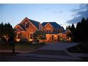 Charming brick house at dusk, illuminated by warm exterior lighting, showcasing its architectural details and inviting ambiance at 120 Slate Dr, Buford, GA 30518