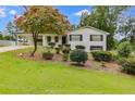 Inviting two-story home showcasing a lush front lawn, mature tree, and an attached carport at 1083 Amelia Sw Dr, Marietta, GA 30060