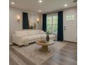 Bright living room with stylish decor, including a cream sectional, round coffee table, and blue curtains at 3199 Nw Delmar Ln, Atlanta, GA 30311