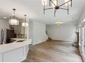 Open-concept living room and kitchen featuring modern lighting, light grey cabinets, and wood floor at 8398 Members Dr, Jonesboro, GA 30236