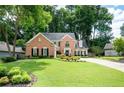 Inviting brick home boasts a lush green lawn and mature trees surrounding the property at 2192 Nine Oaks Nw Dr, Kennesaw, GA 30152