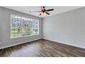 Bright bedroom featuring hardwood floors, a large window with blinds, and a ceiling fan; offering a clean and modern space at 217 Odyssey Turn, Conyers, GA 30012