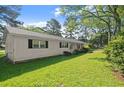 Side view of a cozy one-story home featuring green lawn and mature trees in a suburban neighborhood at 1799 Harmony Rd, Powder Springs, GA 30127