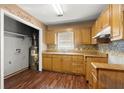 Functional kitchen featuring wooden cabinets, a tiled backsplash, and a laundry area for added convenience at 1799 Harmony Rd, Powder Springs, GA 30127