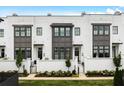Stunning townhouse exterior with white brick, dark trim windows, and beautifully landscaped garden in a modern aesthetic at 6640 Avis Walk, Alpharetta, GA 30005
