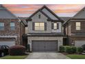 Charming brick townhome featuring a two-car garage, manicured lawn, and classic architectural details at 8215 Harlond Way, Suwanee, GA 30024