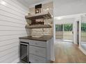 Close-up of a built-in bar with mirrored tile backsplash, floating shelves, and a sleek wine cooler at 100 Biscayne Nw Dr # C1, Atlanta, GA 30309