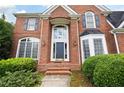 Close-up of a classic brick home with a striking front door and manicured greenery at 2613 Winterthur Main Nw, Kennesaw, GA 30144