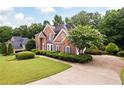 Traditional brick home with manicured bushes, green grass, and a large driveway at 2613 Winterthur Main Nw, Kennesaw, GA 30144