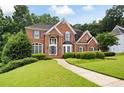 Charming brick home with a lush green lawn, complemented by neatly trimmed shrubs and trees at 2613 Winterthur Main Nw, Kennesaw, GA 30144