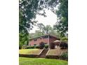 Brick home exterior with patio and stone retaining wall surrounded by lush landscaping at 406 S Hillcrest Sw Dr, Marietta, GA 30064