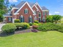 Beautiful two-story red brick home featuring a manicured lawn, black shutters, and mature landscaping around the foundation at 1000 Gunter Ct, Alpharetta, GA 30022