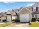 An exterior view of a townhome featuring a garage and well-maintained lawn with clear blue sky at 5351 Paramount View Way, Sugar Hill, GA 30518
