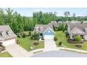 Aerial view of a charming blue home with lush green landscaping in a tranquil suburban neighborhood at 7430 Ramsgate Ct, Cumming, GA 30040