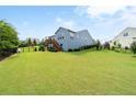 Spacious backyard featuring a large, well-maintained lawn and a wooden deck off the back of the house at 7430 Ramsgate Ct, Cumming, GA 30040