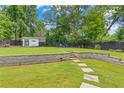 Expansive backyard featuring a stone retaining wall, stepping stone path, a shed, and firepit area at 1442 Pierce Se Ave, Smyrna, GA 30080