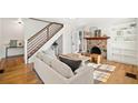 Open-concept living room featuring hardwood floors, stairs, fireplace, and a comfortable sofa at , Atlanta, GA 30344