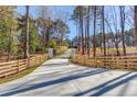 Long paved driveway leading to a modern home with a wooden fence on each side at 0 Thompson Mill Rd, Buford, GA 30519