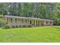 Charming brick home with a covered front porch, well-manicured lawn, and lush, mature landscaping at 1724 Rhonda Ln, Stone Mountain, GA 30087