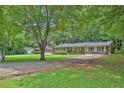 Traditional brick ranch-style home with covered porch, long driveway, and mature trees in a lush green yard at 1724 Rhonda Ln, Stone Mountain, GA 30087