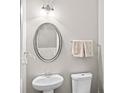 Elegant powder room with oval mirror, pedestal sink and neutral decor at 133 Worthing Ln, Fairburn, GA 30213