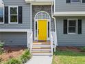 Close-up of a bright yellow front door with stone accents and white trim at 1400 Land Rd, Canton, GA 30114