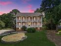 Two-story pink home featuring double front porches and a well-manicured lawn at twilight at 3348 Summit Turf Ln, Snellville, GA 30078