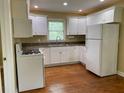 Well-lit kitchen with white cabinets, appliances, and hardwood floors at 410 S Gordon Sw Rd, Mableton, GA 30126