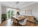 Elegant dining room with modern lighting, hardwood floors, and large windows showcasing garden views at 10880 Windham Way, Alpharetta, GA 30022