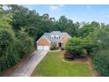Exterior view of a brick home with a well-manicured lawn and surrounded by lush trees at 10880 Windham Way, Alpharetta, GA 30022