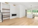 Open-concept living space featuring hardwood floors, marble fireplace, built-in shelves, and adjacent kitchen at 11560 Serenbe Ln, Chattahoochee Hills, GA 30268
