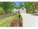 Beautiful white home with a manicured lawn, flower beds, and a long driveway, surrounded by lush green trees at 4210 Platinum Ct, Hoschton, GA 30548