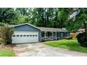 Cozy home featuring a single-car garage, a quaint front porch, and a well-manicured lawn at 5177 Mccarter Sta, Stone Mountain, GA 30088