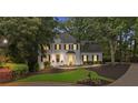 Charming two-story home with manicured lawn, mature trees, enhanced by tasteful exterior lighting and black shutters at 1755 Noblin Summit Dr, Duluth, GA 30097