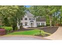 Charming two-story home featuring a manicured lawn, mature trees, and a welcoming entrance with black shutters at 1755 Noblin Summit Dr, Duluth, GA 30097