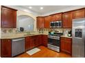 Well-lit kitchen with stainless steel appliances, granite countertops, and cherry wood cabinets at 4879 Seldon Se Way, Smyrna, GA 30080