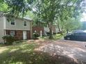 View of the exteriors of the townhouse with green shutters and driveway, surrounded by trees and greenery at 8955 Stonebridge Blvd, Douglasville, GA 30134